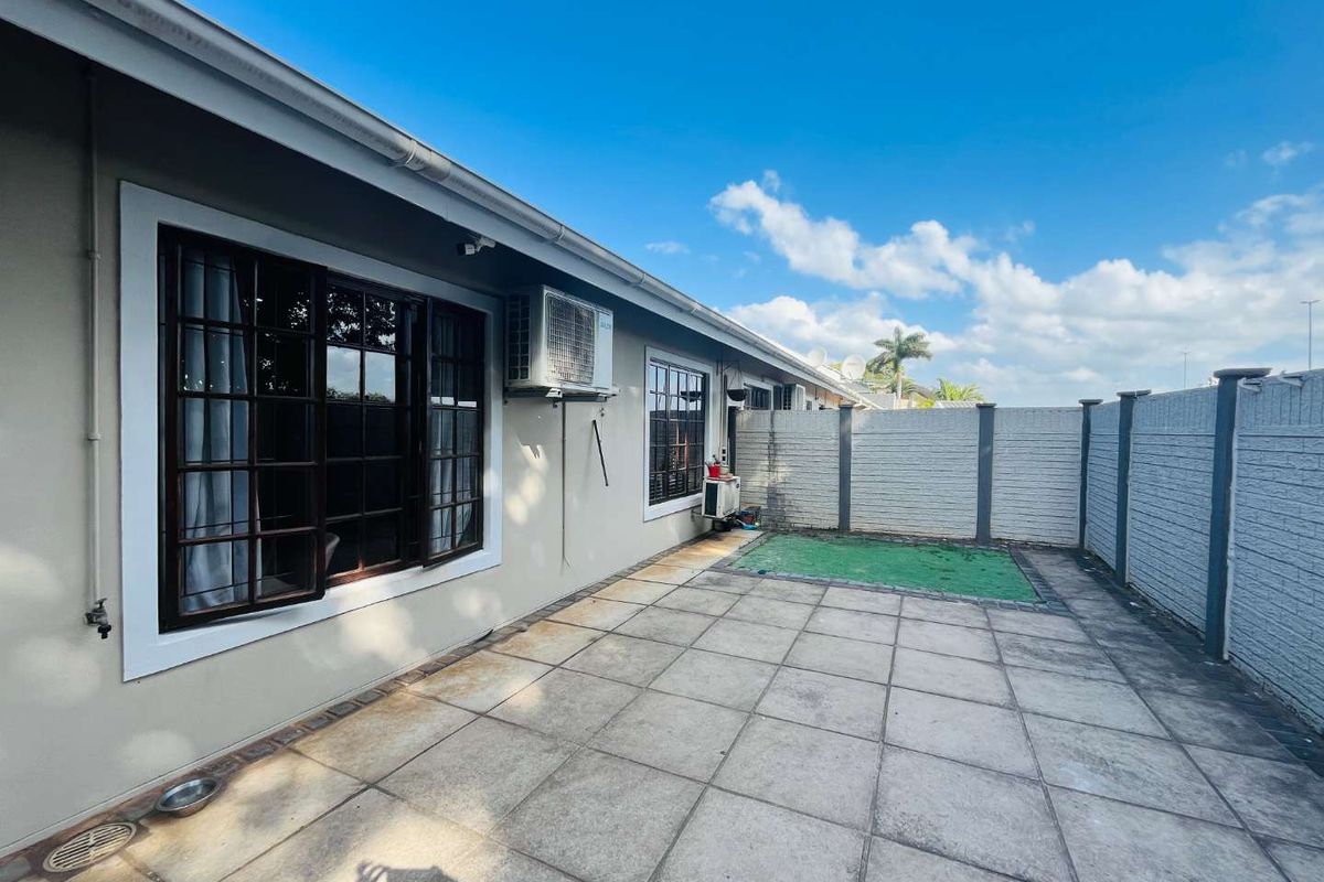 A private rear patio area featuring paved flooring, perimeter boundary walls, and wall-mounted air conditioning units.