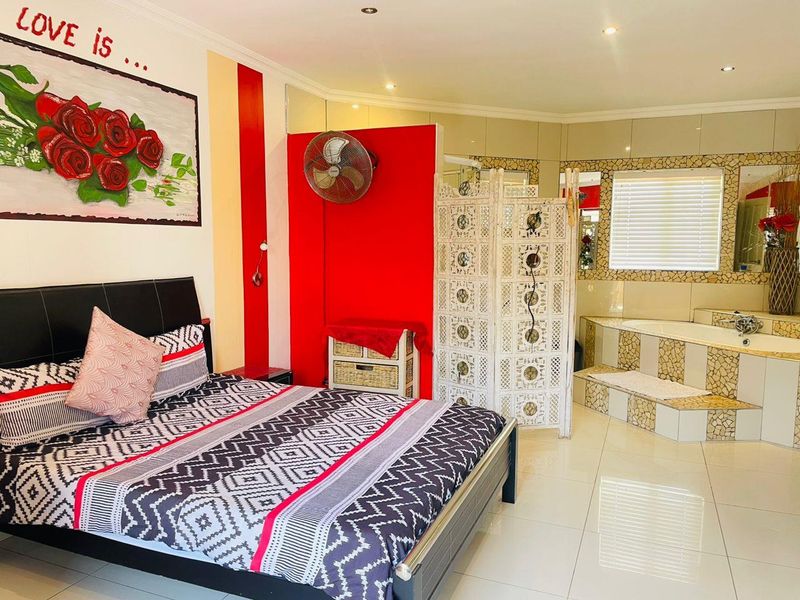 Spacious bedroom featuring an integrated en-suite bathtub area with tiled finishes, recessed lighting, and polished floor tiles.
