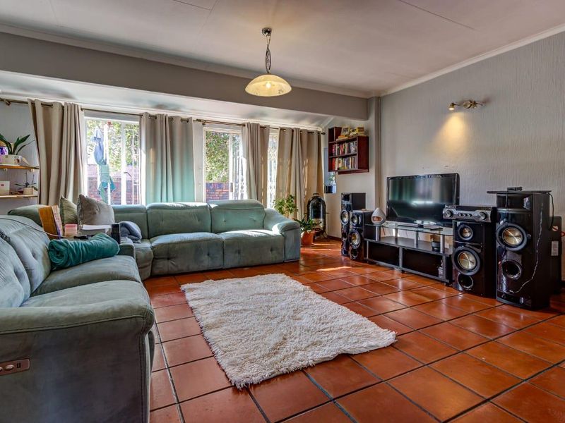 Spacious living room featuring terracotta floor tiles, large sliding glass doors providing natural light, and built-in shelving.