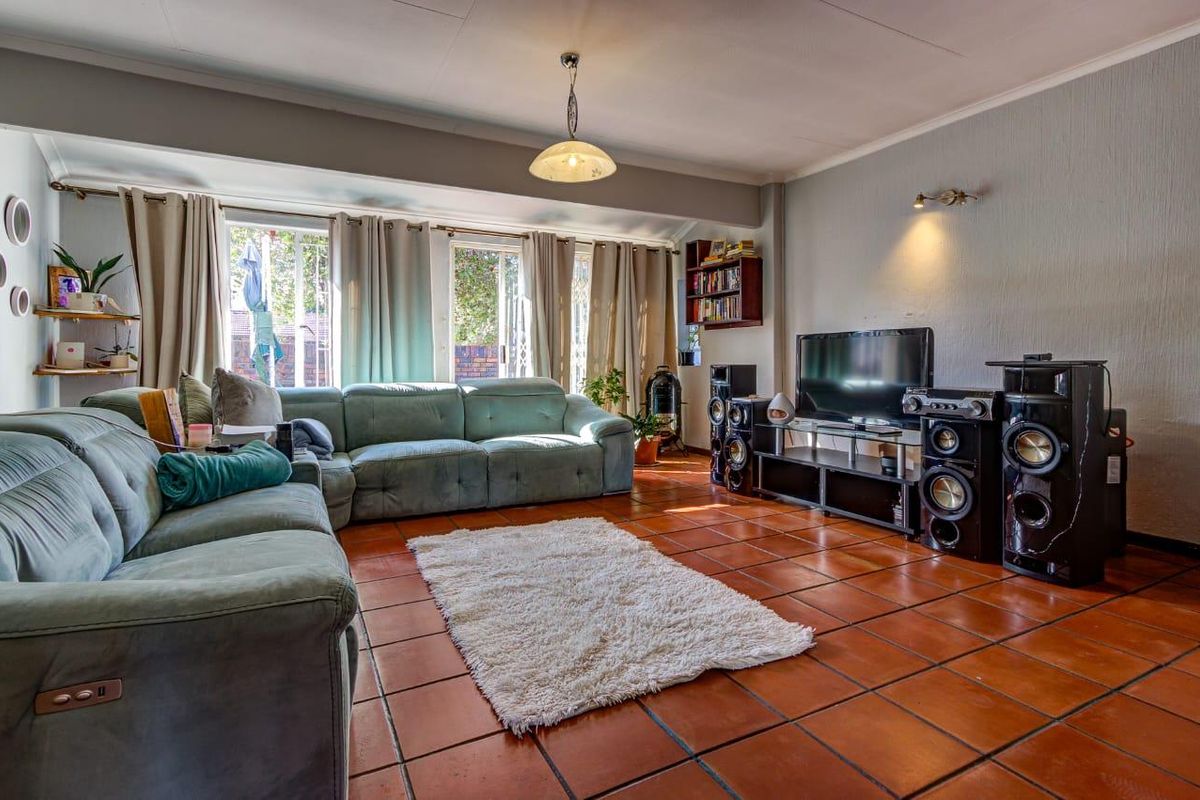 Spacious living room featuring terracotta floor tiles, large sliding glass doors providing natural light, and built-in shelving.