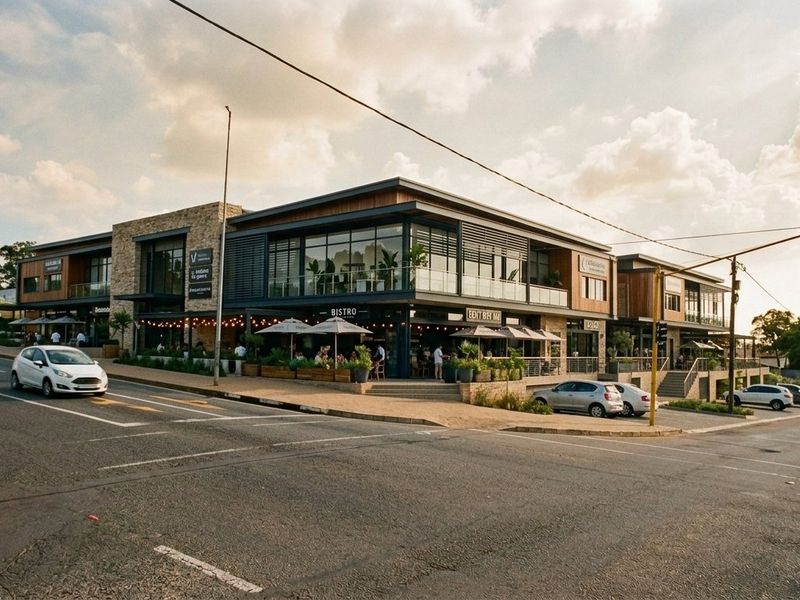 Modern mixed-use commercial building featuring contemporary stone and glass architecture with ground-level bistro terrace and upper-level balcony spaces.