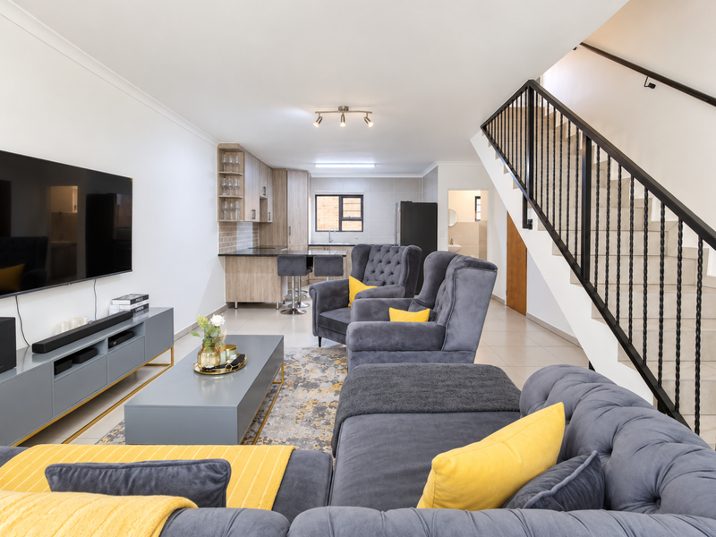 Modern open-plan living area featuring a contemporary kitchen with granite countertops and a staircase with a sleek metal balustrade.