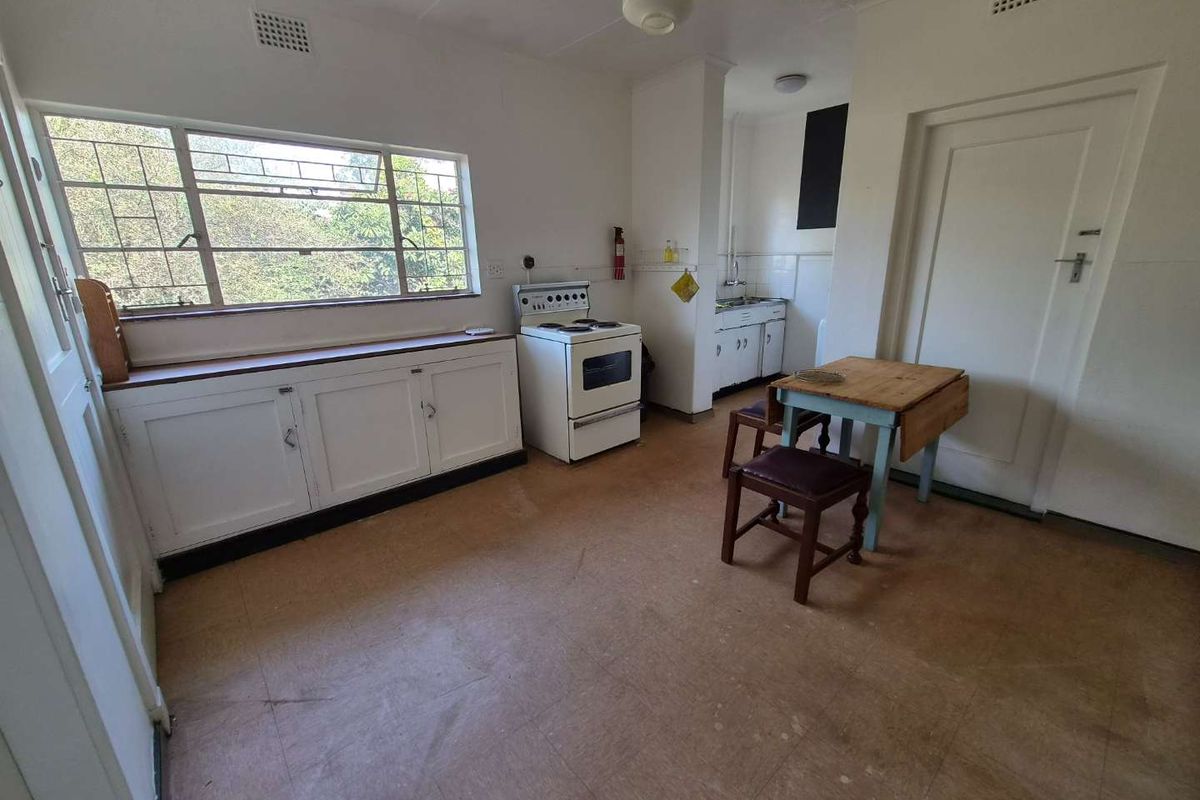 A dated kitchen featuring original built-in cabinetry, a freestanding stove, and large windows, offering significant potential for a modern renovation.