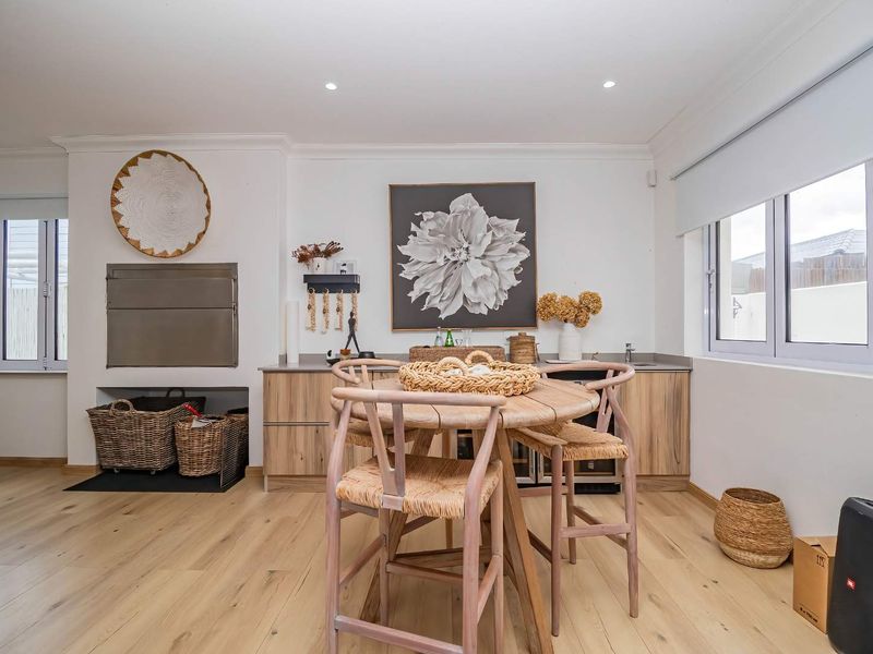Modern open-plan living area featuring light timber flooring, built-in braai, and sleek cabinetry with stone countertops, creating a bright and functional entertainment space.