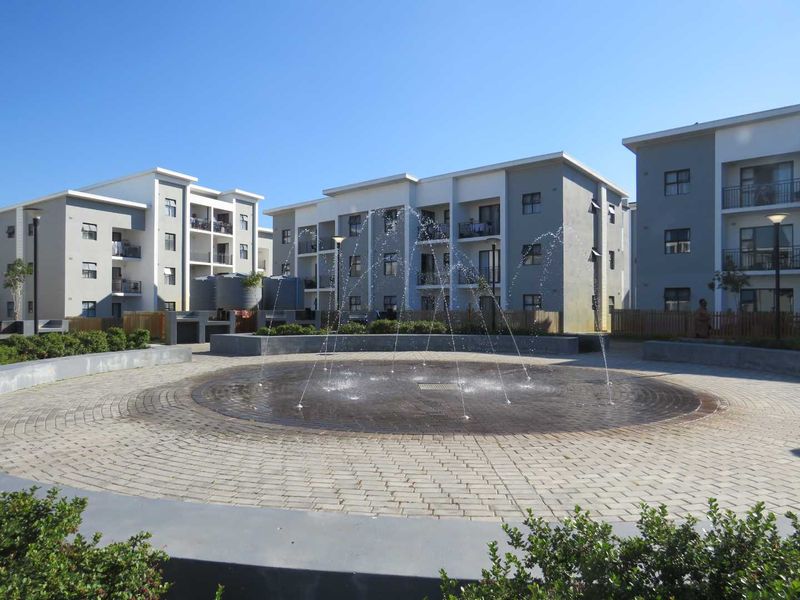 A well-maintained communal courtyard featuring a central water fountain surrounded by modern multi-story apartment buildings with balconies.