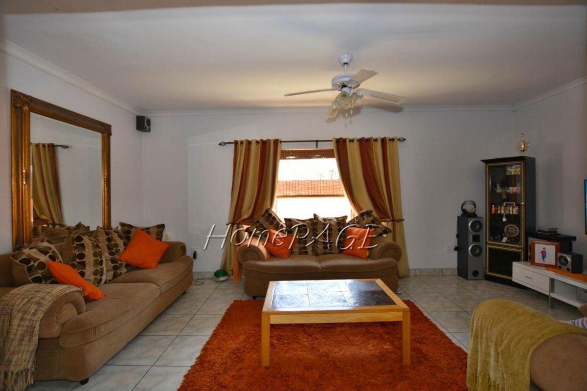 A living room featuring tiled flooring, a ceiling fan, and a large wall-mounted mirror.