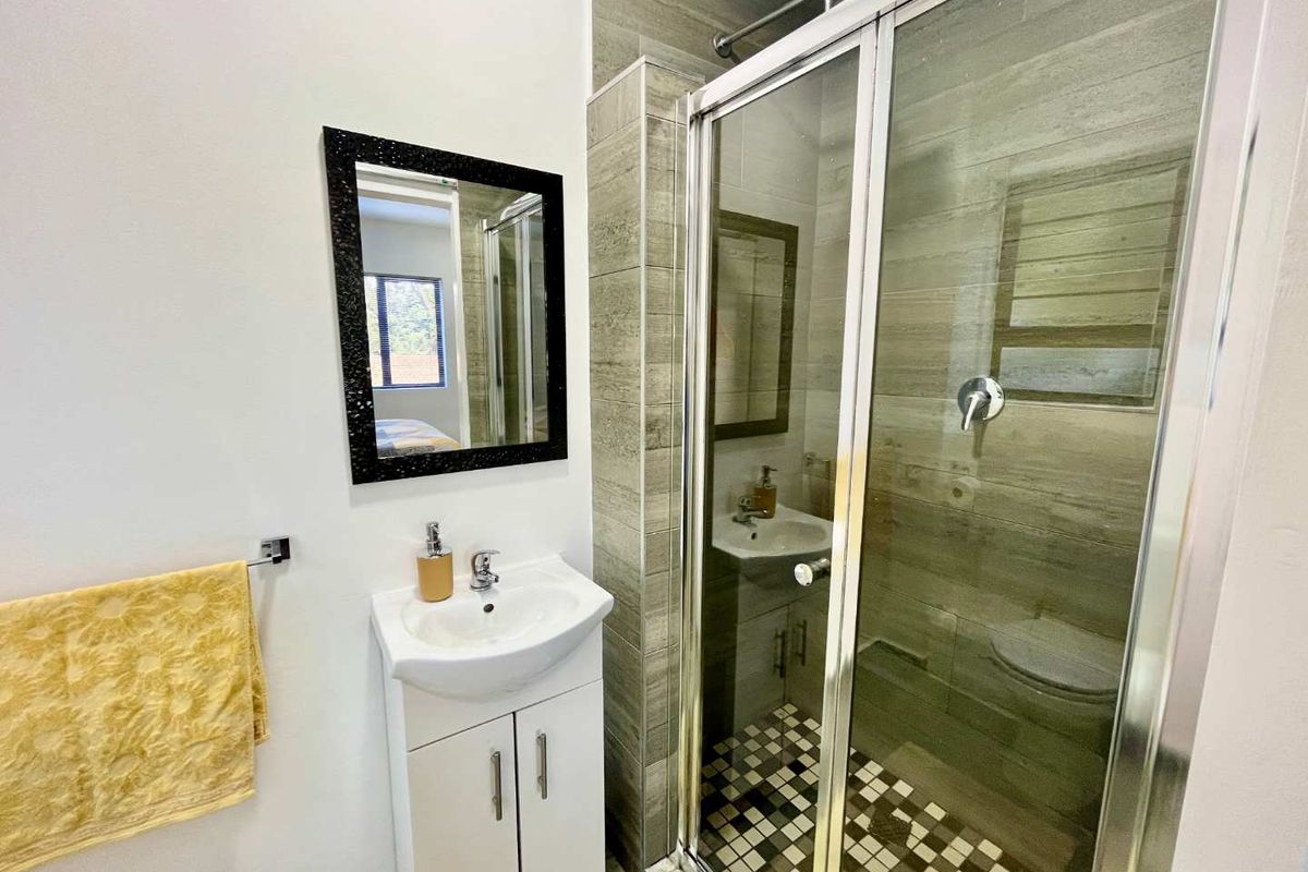 Modern bathroom featuring a glass-enclosed shower with textured wall tiles, a pedestal vanity with basin, and contemporary fixtures.
