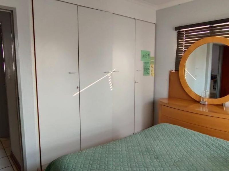 Bedroom featuring built-in cupboards and venetian blinds, with an adjoining bathroom visible through the doorway.