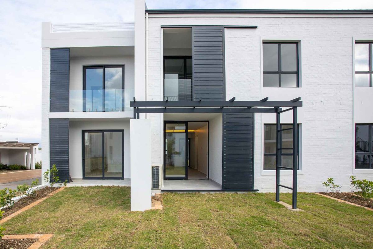 Modern rear elevation of an apartment featuring a private garden, pergola, glass balustrades, and large sliding doors providing seamless indoor-outdoor flow.