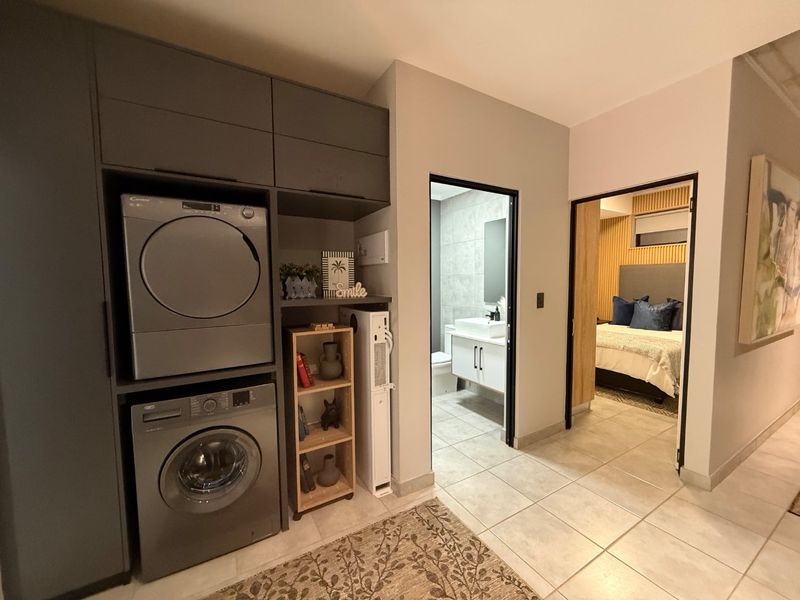 A functional laundry area featuring built-in cabinetry, providing direct access to an adjacent bathroom and bedroom.
