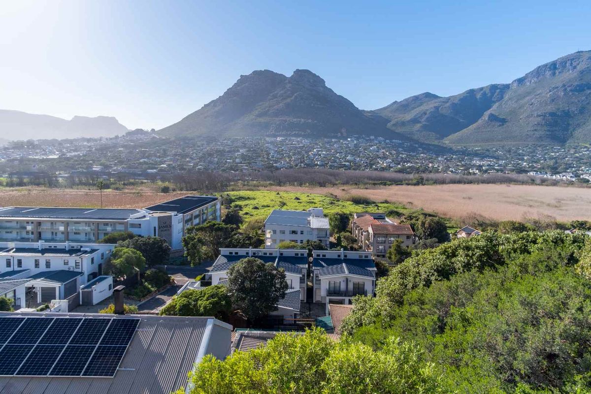 Aerial view of the apartment complex featuring solar panels on the roof, set against a scenic mountain and valley landscape.