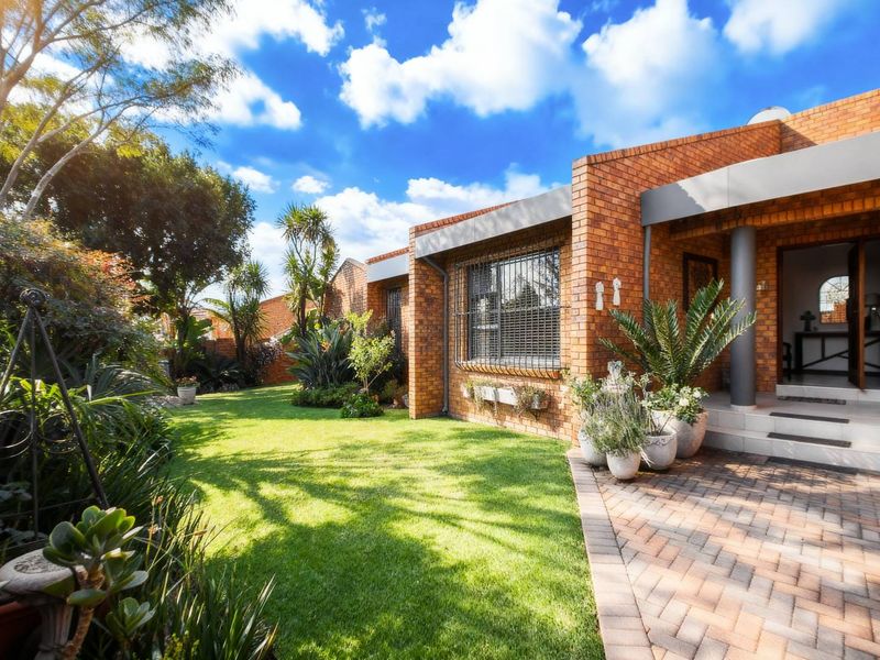 A well-maintained face brick home featuring a paved entrance area and a lush, landscaped front garden.