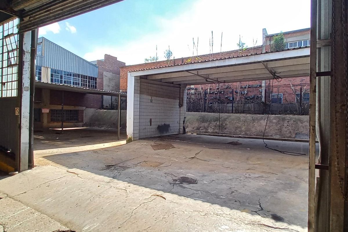 Industrial yard area featuring a covered loading bay, concrete flooring, and steel-framed structure, suitable for logistics or manufacturing operations.