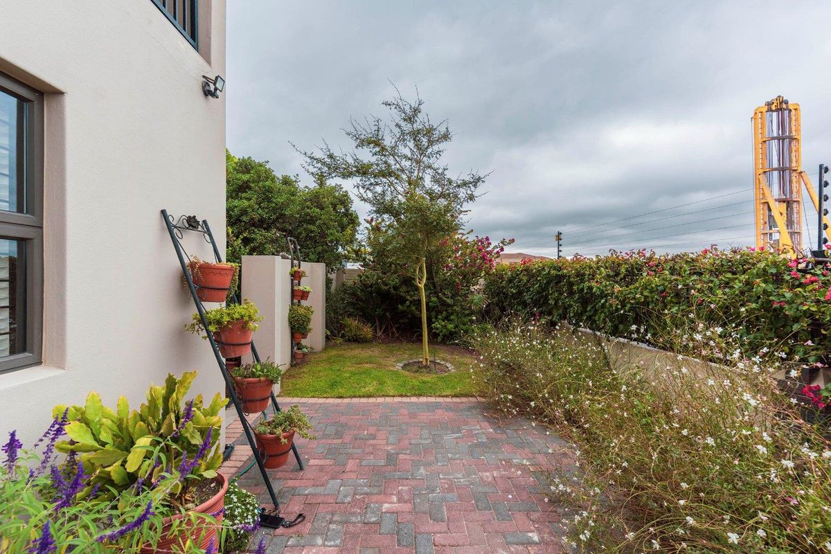 A well-maintained rear garden featuring a brick-paved patio area, established landscaping, and a boundary wall.