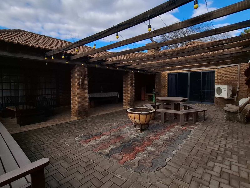 Spacious outdoor patio area featuring a timber pergola, brick paving, and direct access to the main house through sliding glass doors.