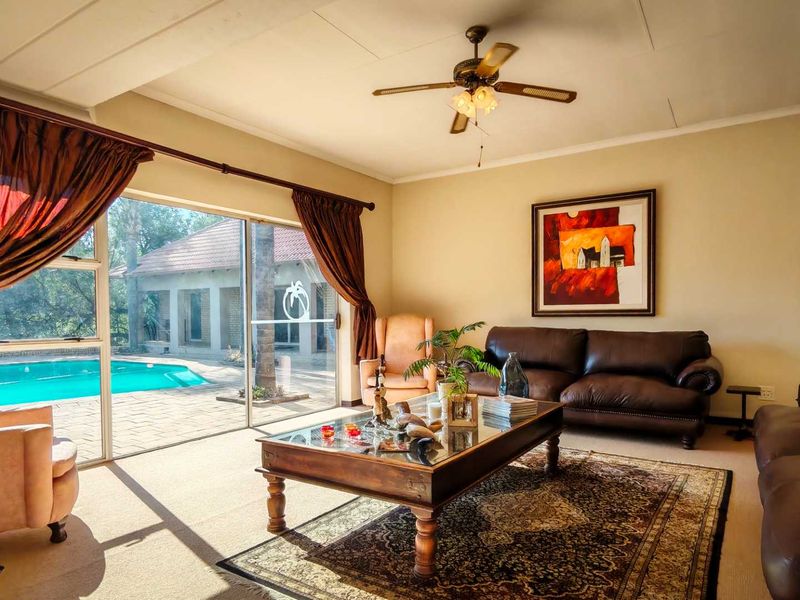 Spacious living room featuring a ceiling fan and large sliding glass doors that provide direct access to the outdoor pool area.