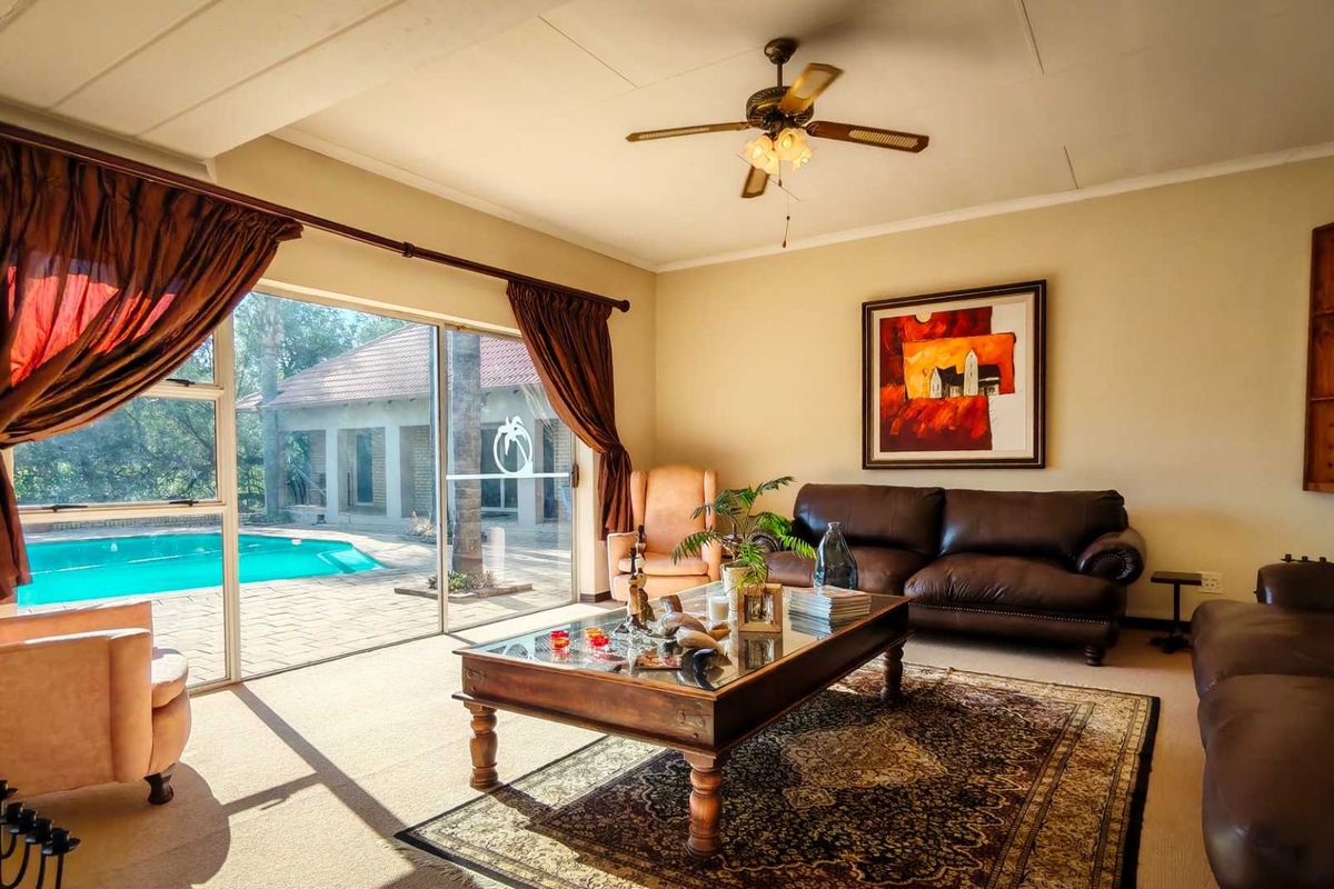 Spacious living room featuring a ceiling fan and large sliding glass doors that provide direct access to the outdoor pool area.