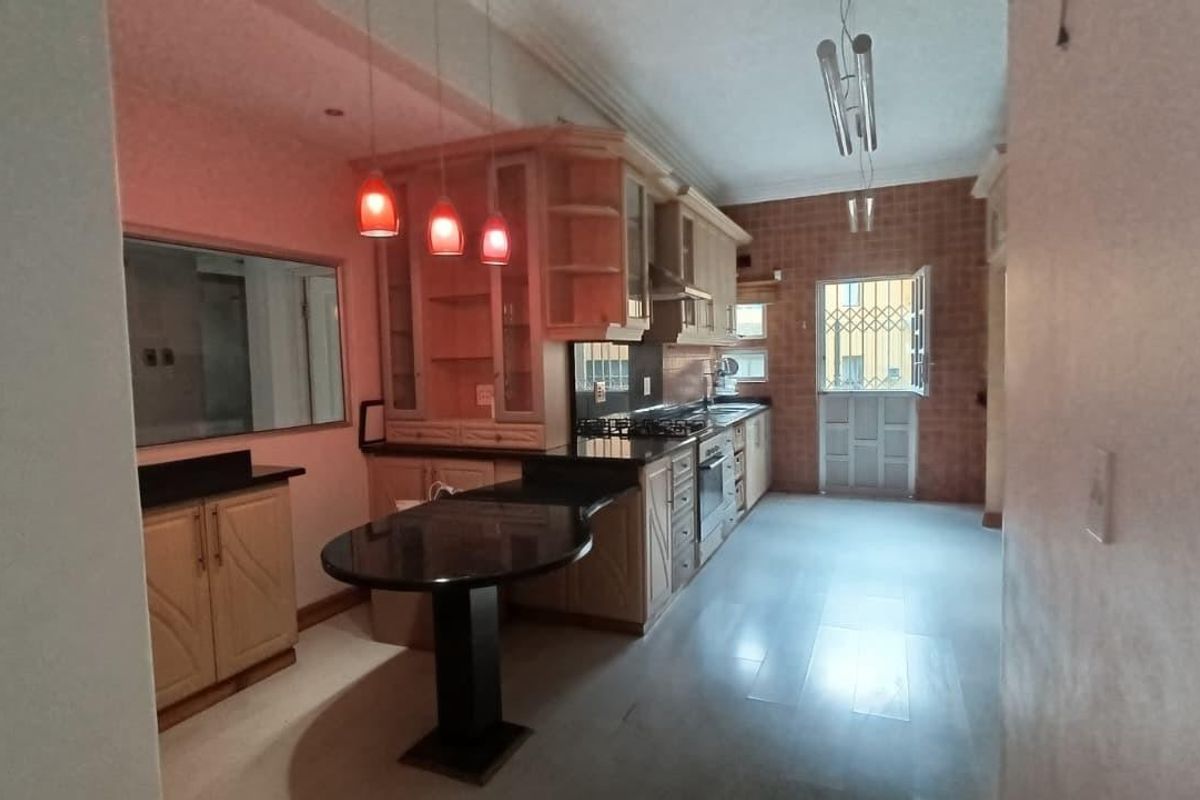 A functional kitchen featuring light wood cabinetry, granite countertops, a breakfast bar, and integrated appliances, with direct access to the exterior.