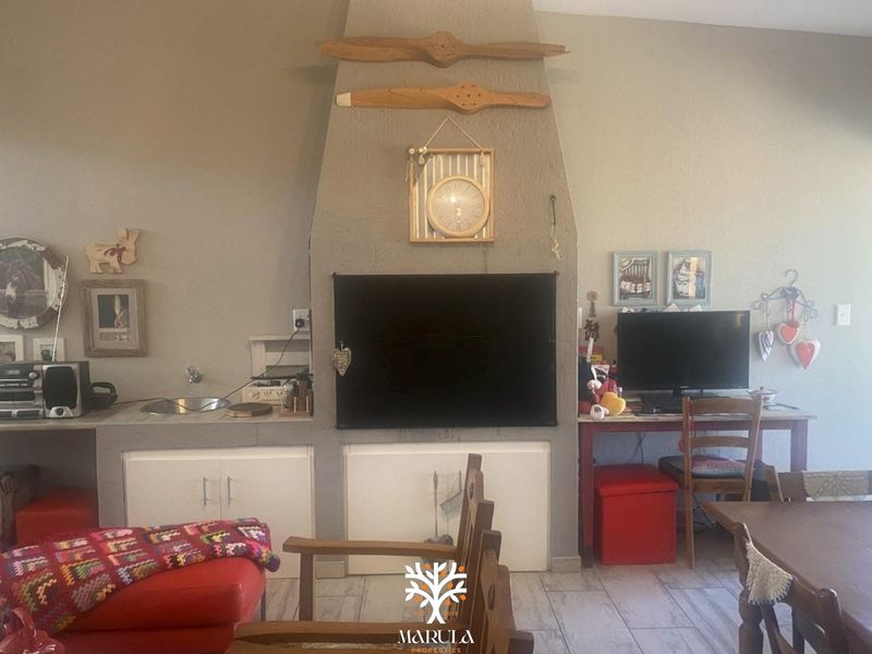 Living area featuring a central built-in fireplace, integrated cabinetry with a sink, and tiled flooring.