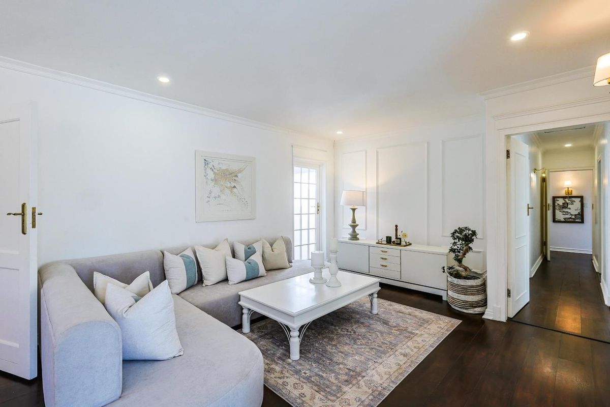 A bright and well-maintained living room featuring dark hardwood flooring, decorative wall paneling, and recessed ceiling lighting.