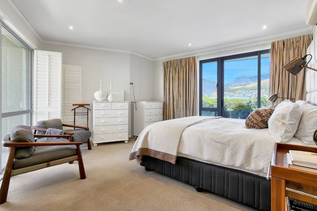 Spacious bedroom featuring neutral carpeting, recessed lighting, and large sliding glass doors that provide natural light and access to a balcony with scenic views.