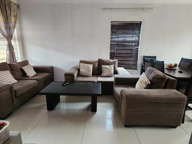 Open plan living and dining area featuring tiled flooring and window treatments, providing a functional space for relaxation and meals.
