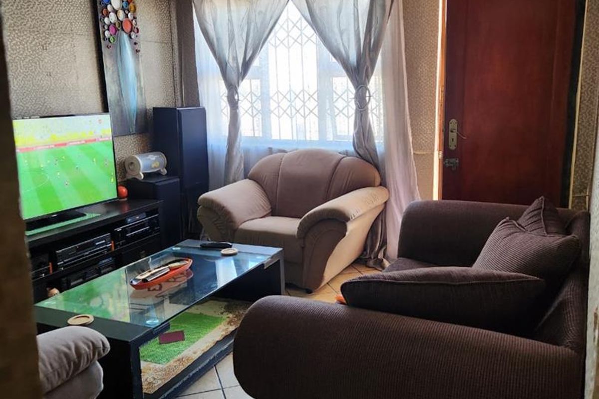 A living room featuring tiled flooring, a security gate, and an air conditioning unit, with visible wear on the wall finishes and ceiling.