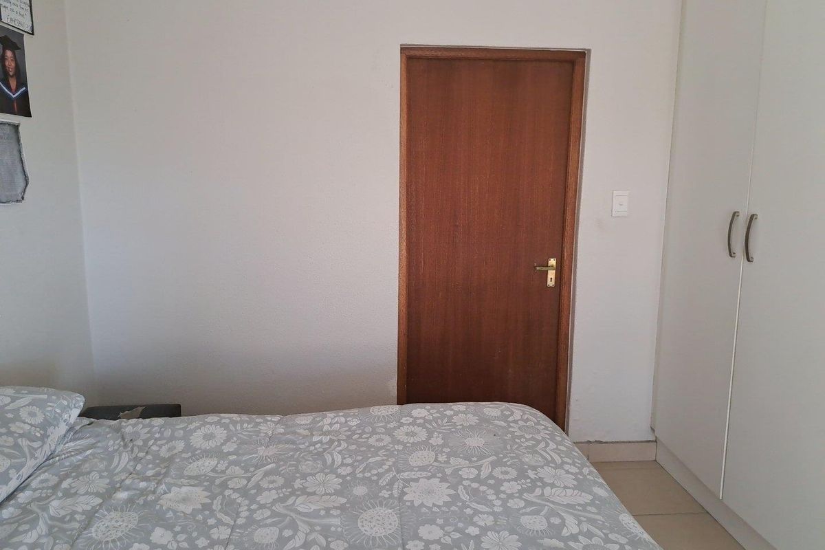 A bedroom featuring built-in white cupboards and a wooden door, providing functional storage and access within the room.