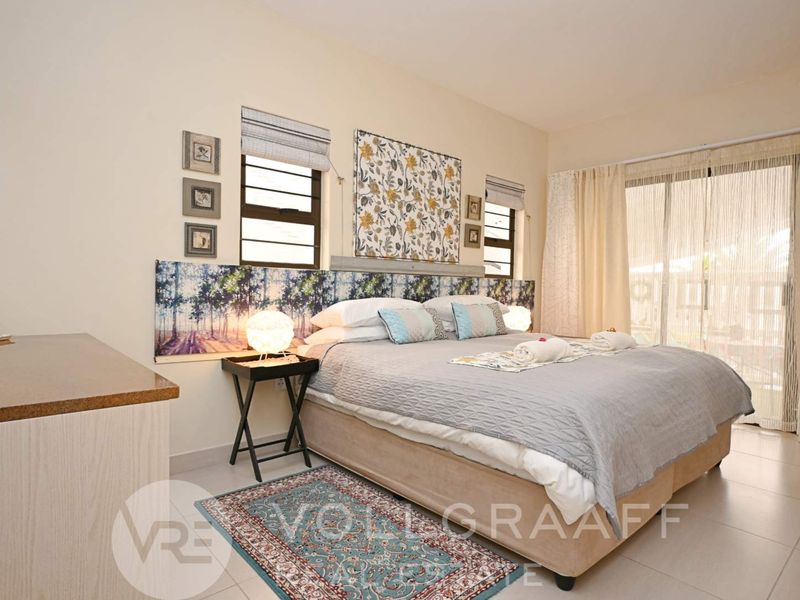 A well-maintained bedroom featuring tiled flooring, a built-in headboard, and a sliding glass door providing access to the exterior.