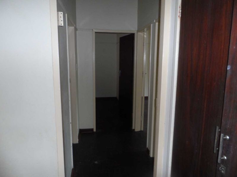 A narrow interior hallway featuring dark flooring and built-in cupboard storage, providing access to multiple rooms within the apartment.