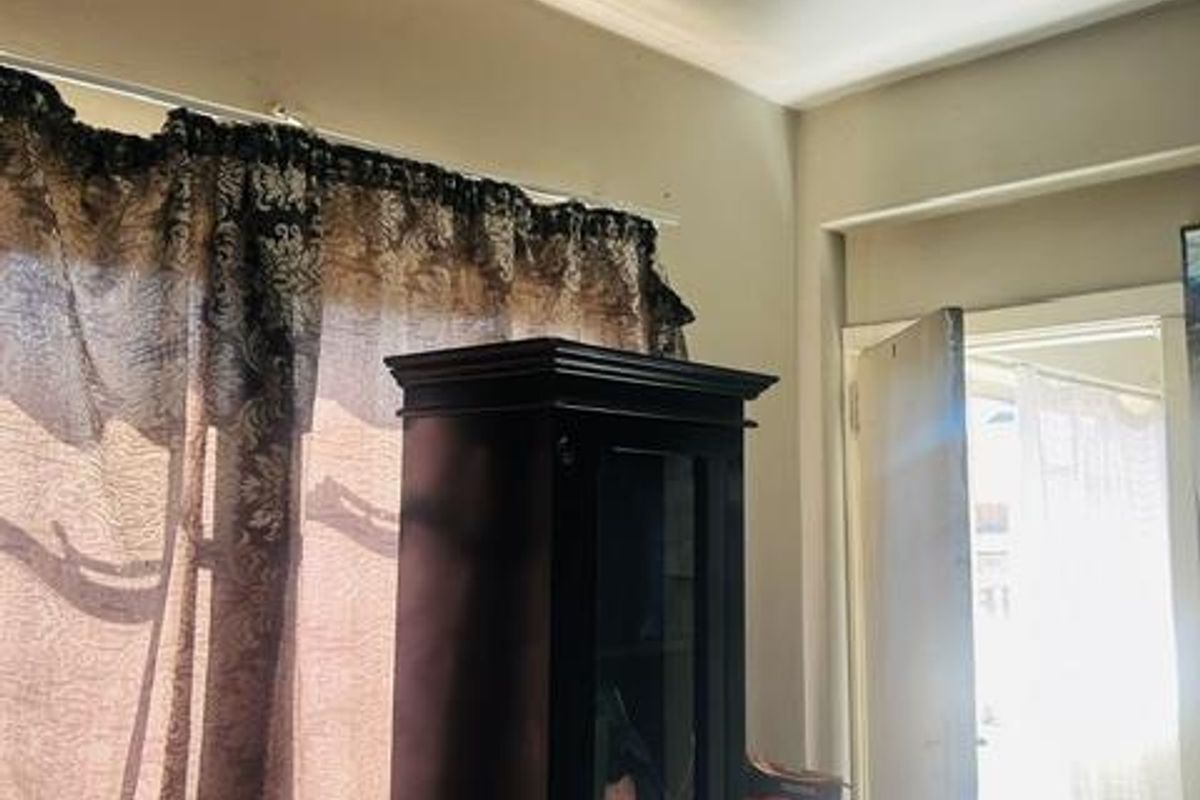 A bedroom interior featuring a window with a curtain rod and a doorway leading to an adjacent space.