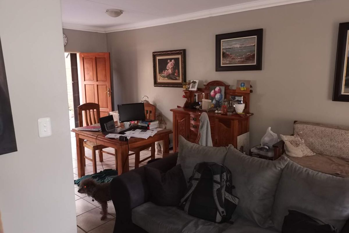 A living area featuring tiled flooring, crown molding, and a wooden door leading to an exterior space.