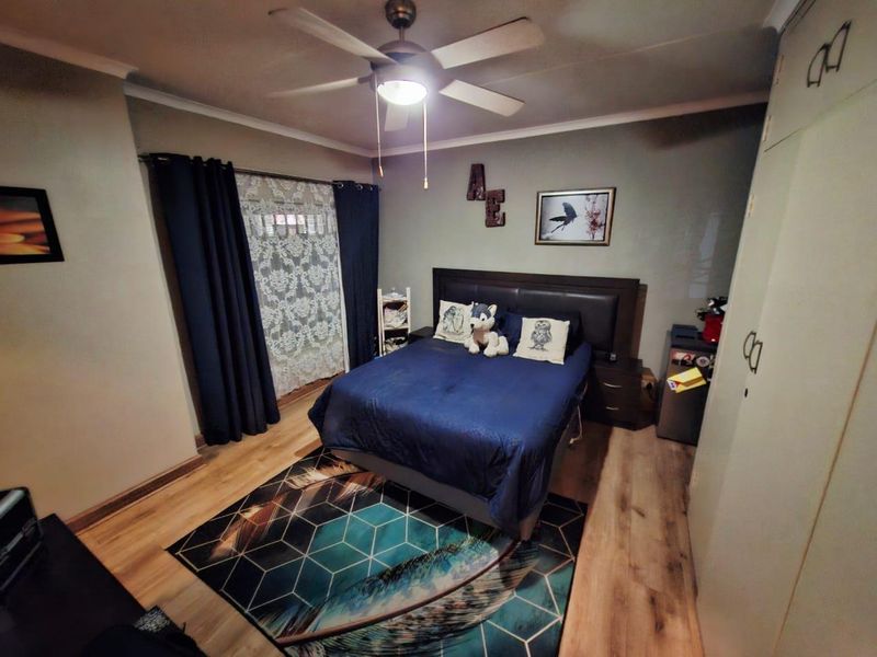 A well-maintained bedroom featuring laminate flooring, a ceiling fan, and built-in cupboards, providing a functional and comfortable living space.