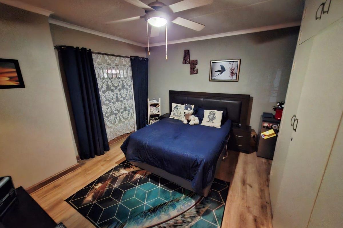 A well-maintained bedroom featuring laminate flooring, a ceiling fan, and built-in cupboards, providing a functional and comfortable living space.