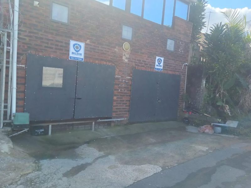 Exterior view of a double garage featuring brick facade and security signage, with a concrete driveway area.