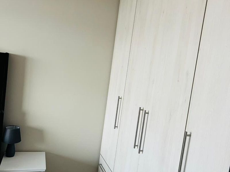 A bedroom featuring light wood-finish built-in cupboards and modern laminate flooring, providing clean and functional storage space.