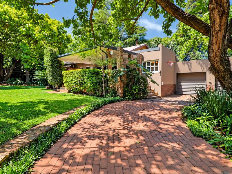 Front view of the property featuring a brick driveway, established garden, stone-accented entrance, and a single garage.