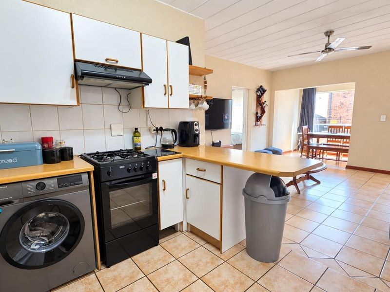 Open-plan kitchen and living area featuring tiled flooring, built-in cabinetry, gas stove, and a ceiling fan, offering a functional layout for daily living.