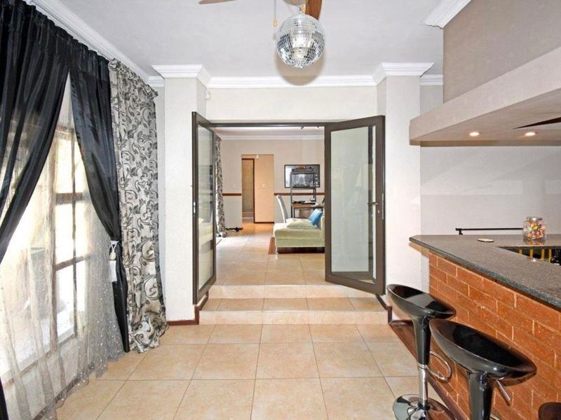 Open plan living area featuring a brick breakfast bar with granite countertop, tiled flooring, and double glass doors leading to an adjacent room.
