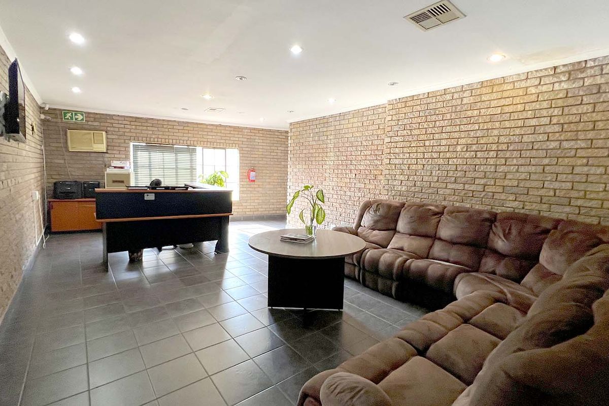 Spacious industrial-style living area featuring exposed brick walls, tiled flooring, and recessed lighting, suitable for a versatile office or reception space.