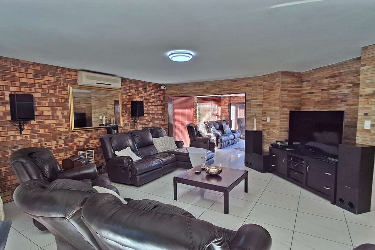 Spacious living room featuring exposed brick walls, tiled flooring, and direct access to an outdoor area through sliding glass doors.