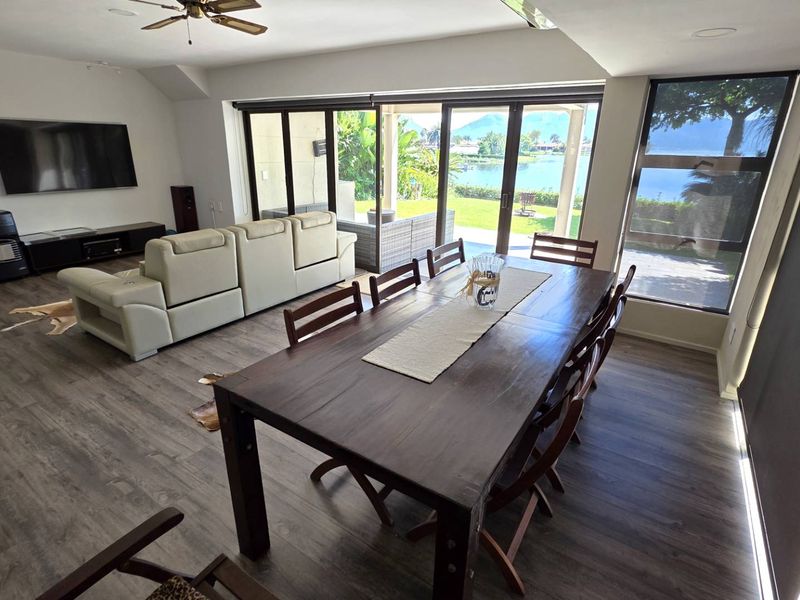 Spacious open-plan living and dining area featuring modern laminate flooring, recessed lighting, and large sliding glass doors that open to a scenic outdoor view.