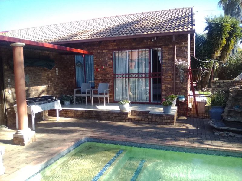 Rear exterior view featuring a brick facade, covered patio area, and a swimming pool.