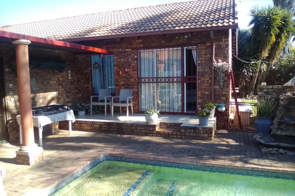 Rear exterior view featuring a brick facade, covered patio area, and a swimming pool.