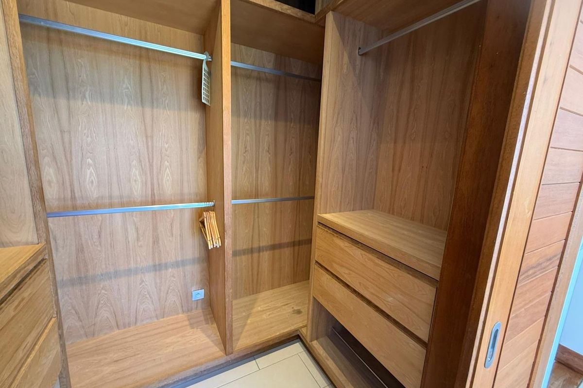 A walk-in closet featuring custom built-in wooden cabinetry with hanging rails, shelving, and integrated drawers.