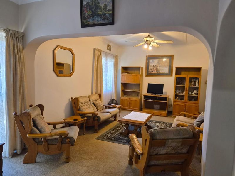 A traditional living room featuring a central ceiling fan and a distinctive arched entryway connecting to the adjacent space.