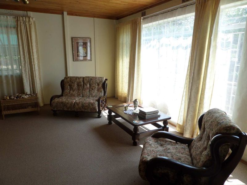 A living room featuring a timber ceiling, carpeted flooring, and large windows that provide ample natural light.