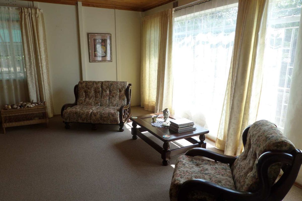 A living room featuring a timber ceiling, carpeted flooring, and large windows that provide ample natural light.