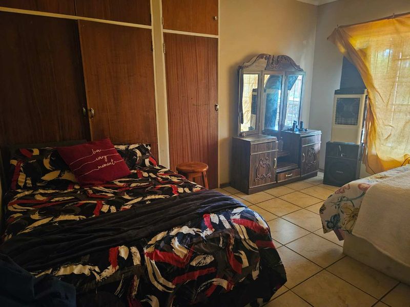 A bedroom featuring built-in wooden cupboards and tiled flooring, offering a functional space with potential for modernization.