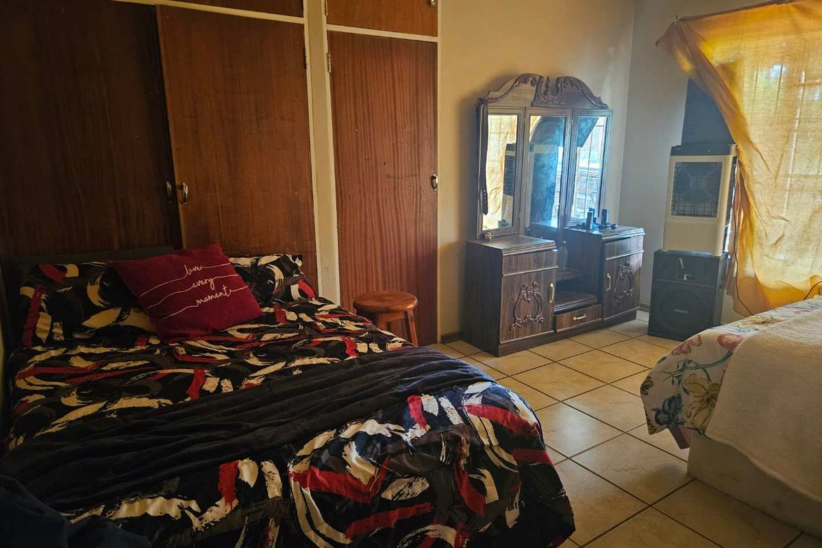 A bedroom featuring built-in wooden cupboards and tiled flooring, offering a functional space with potential for modernization.